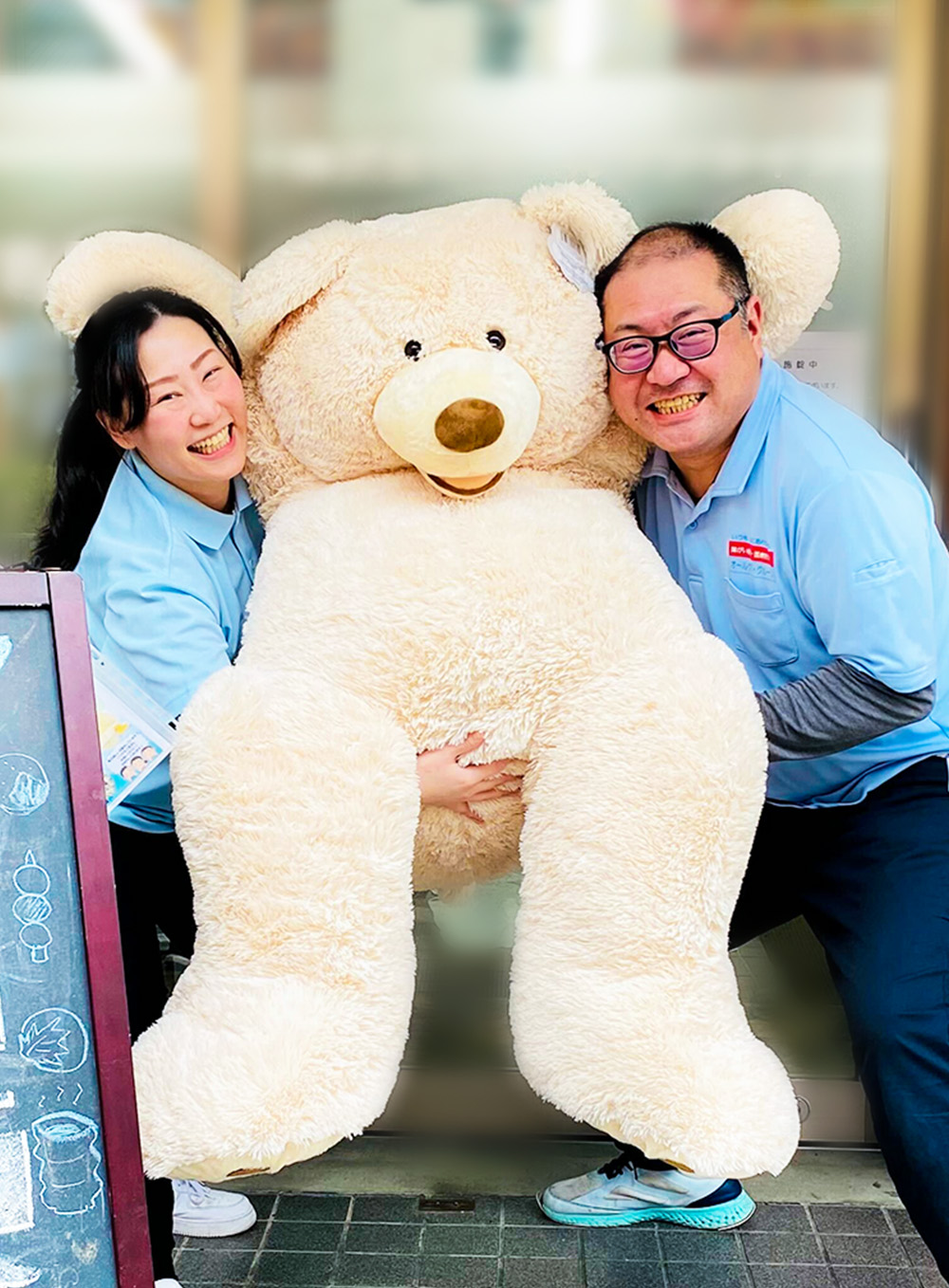 笑顔のスタッフとくまのぬいぐるみ
